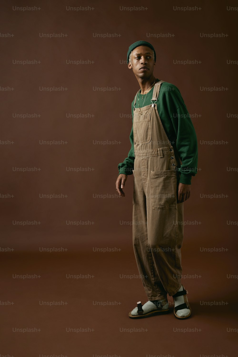 a man in overalls and a green sweater