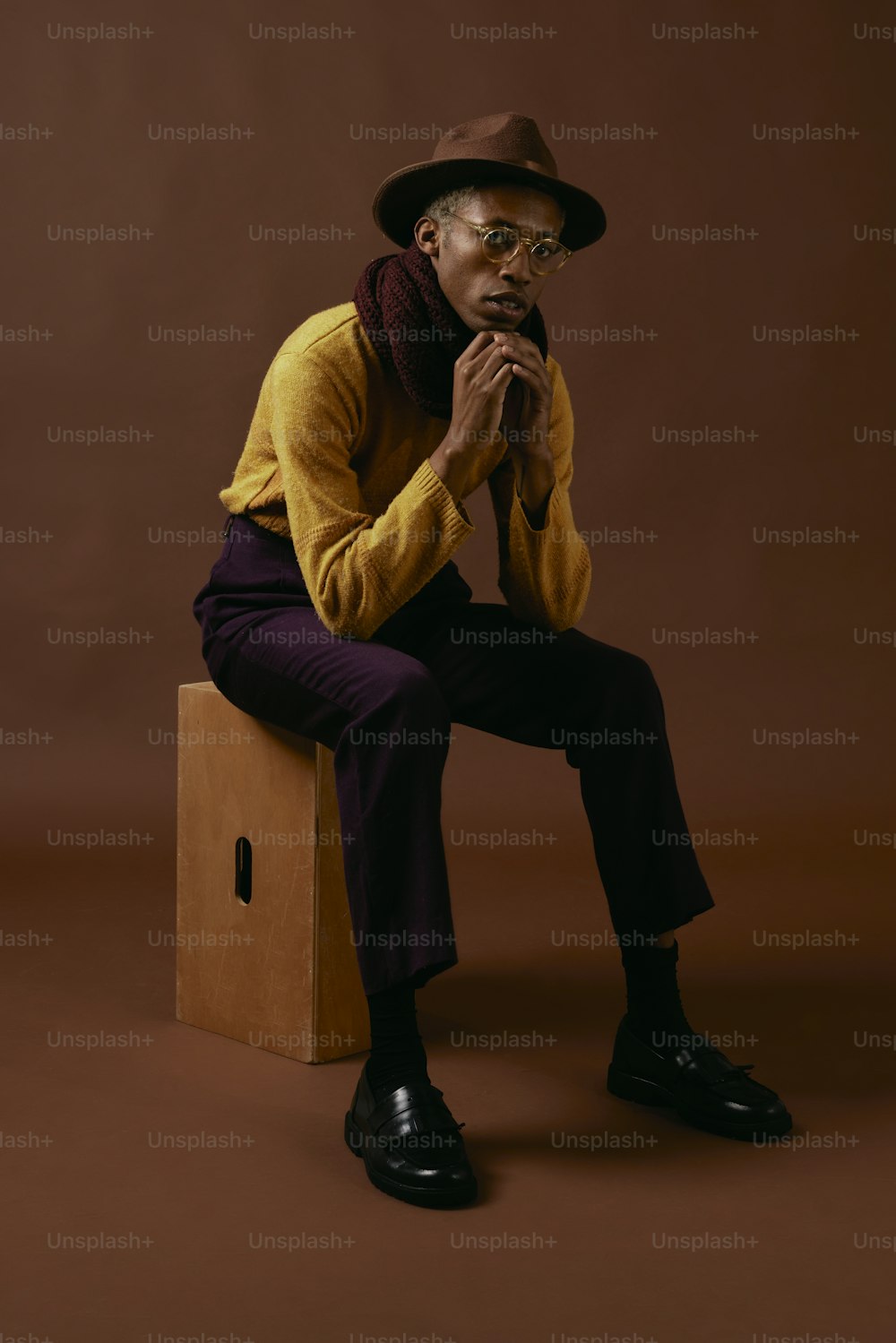 a man sitting on top of a box wearing a hat