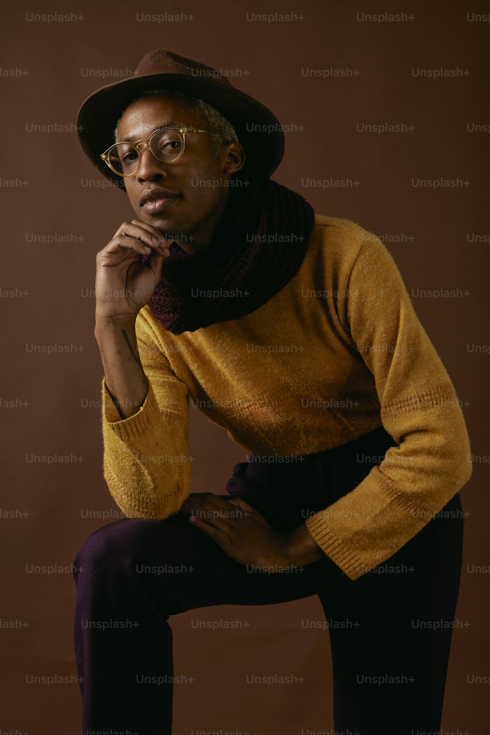 a man in a yellow sweater and hat poses for a picture