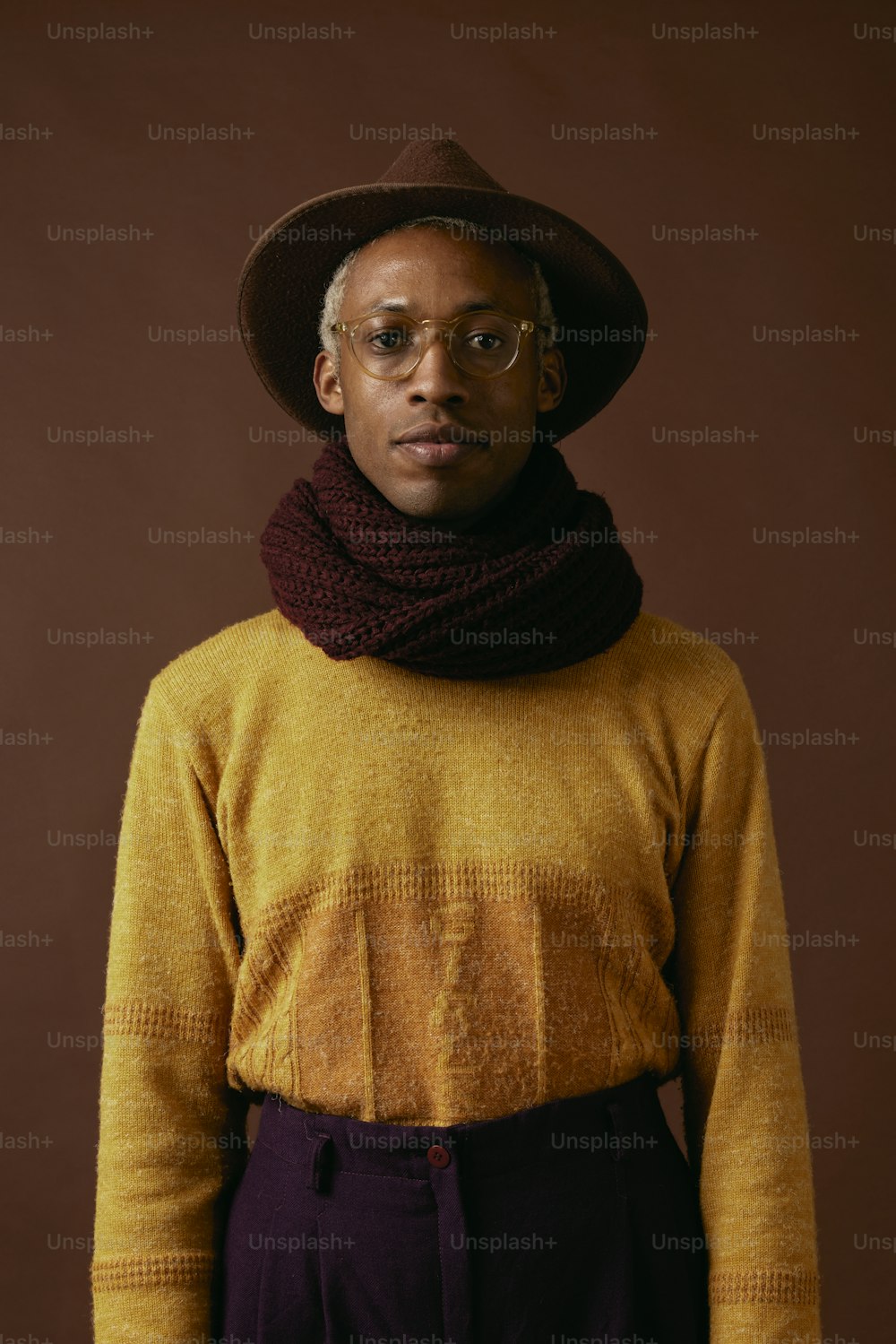 a man wearing a yellow sweater and a brown hat