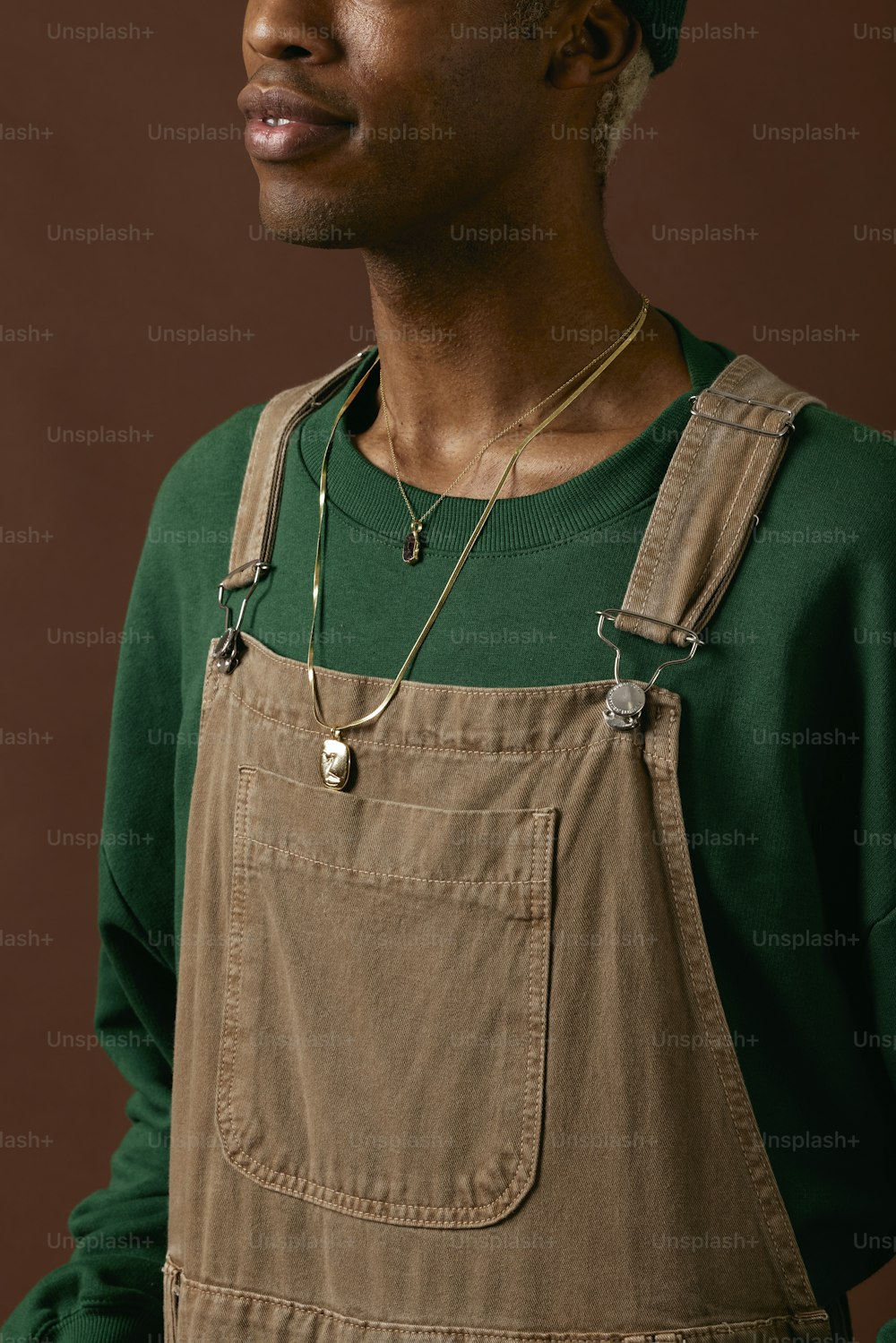 a man wearing a green shirt and brown overalls