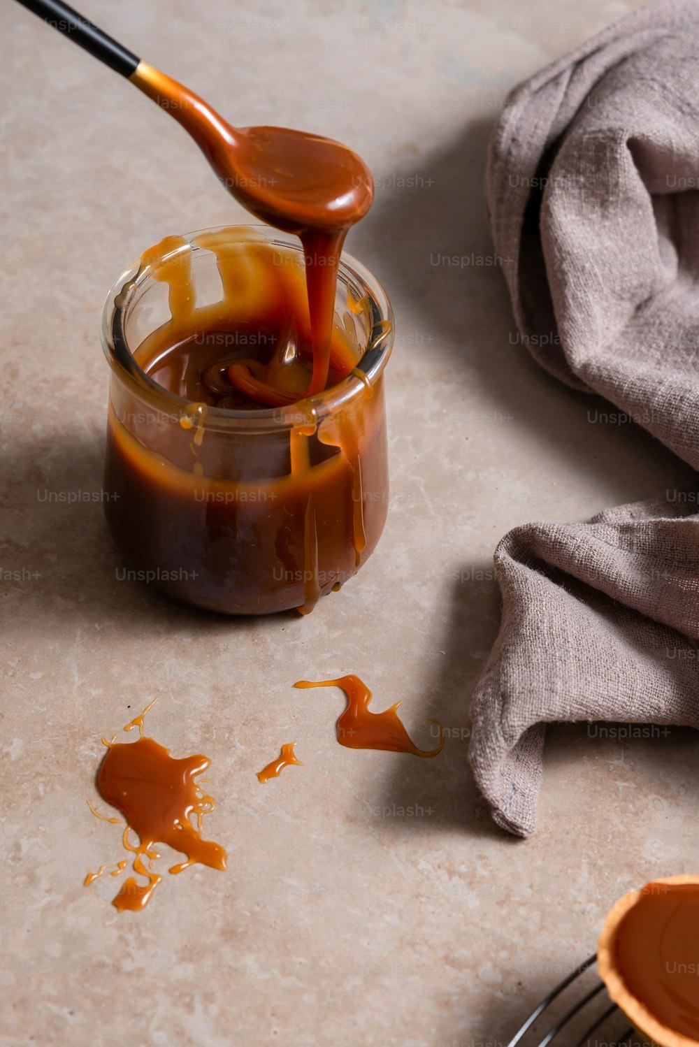a spoon is pouring caramel sauce into a jar