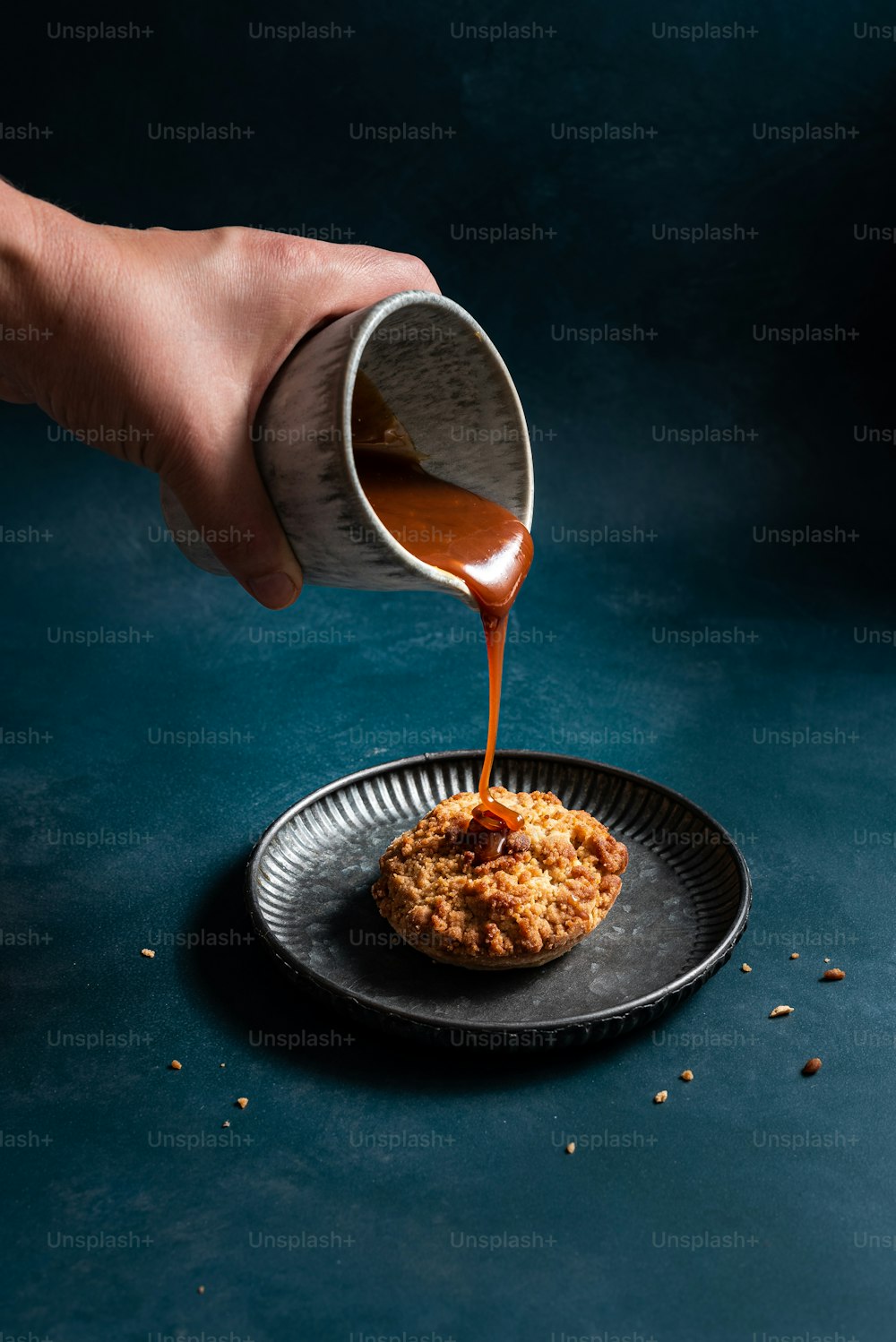Una persona vertiendo salsa en una galleta en un plato