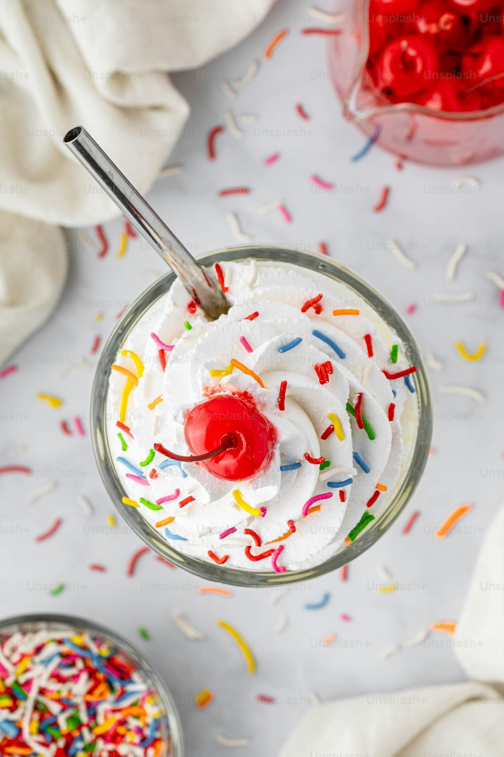 a cup of ice cream with sprinkles and a cherry