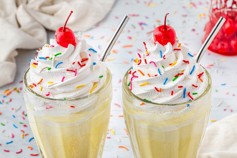 two glasses filled with whipped cream and sprinkles