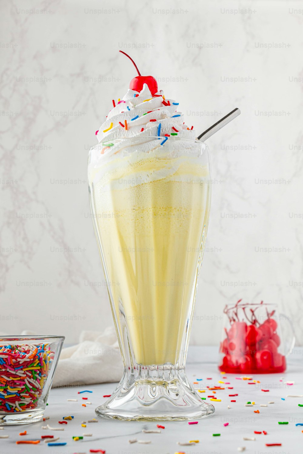 a yellow drink with sprinkles and a cherry on top