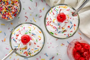 two glasses of ice cream with sprinkles and a cherry
