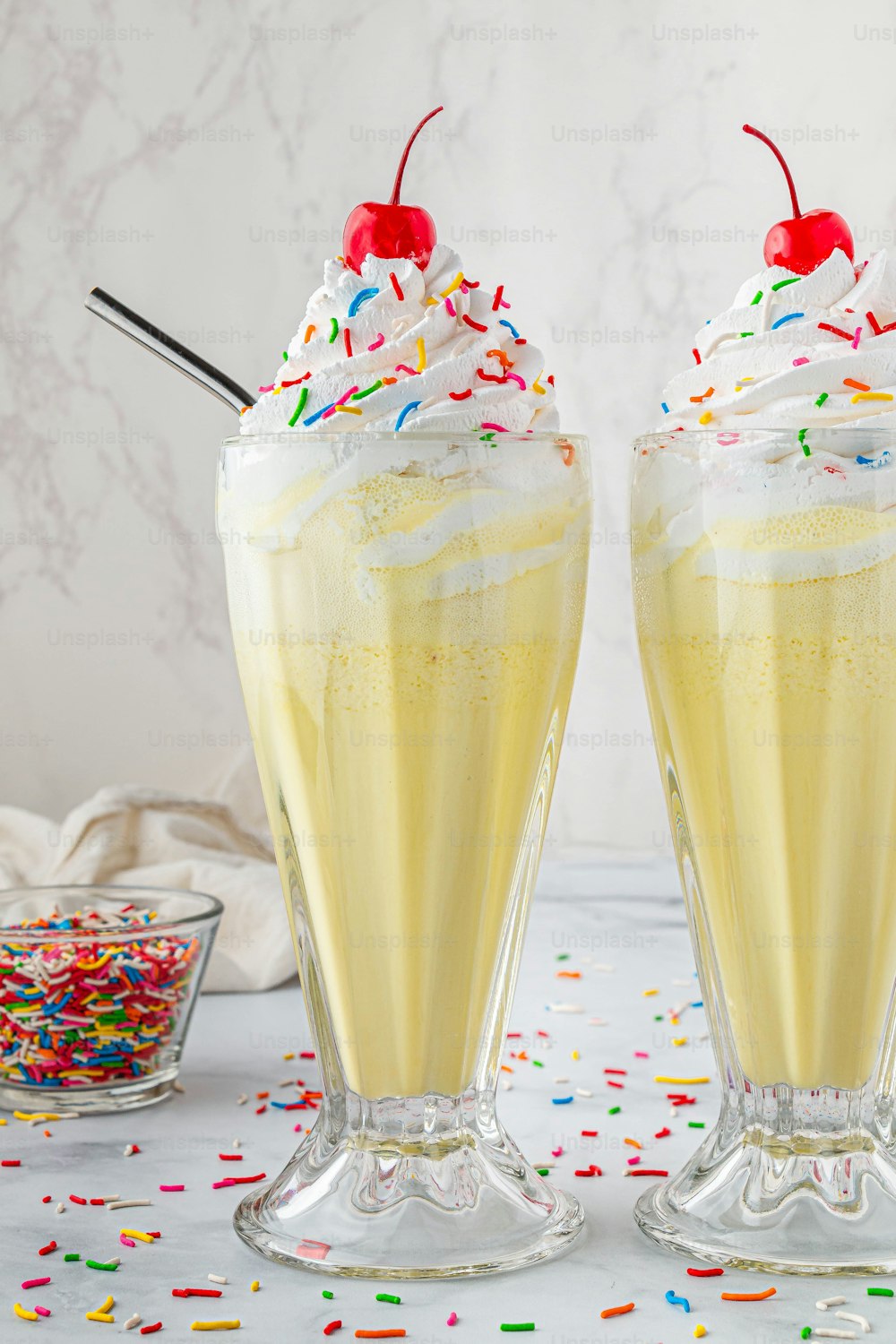two glasses filled with yellow liquid and topped with sprinkles