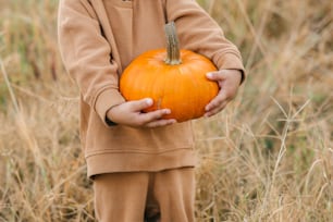 a little boy holding a pumpkin in his hands