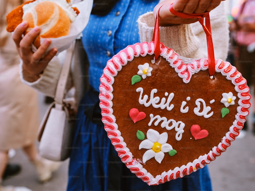 uma mulher segurando um biscoito em forma de coração com uma mensagem nele