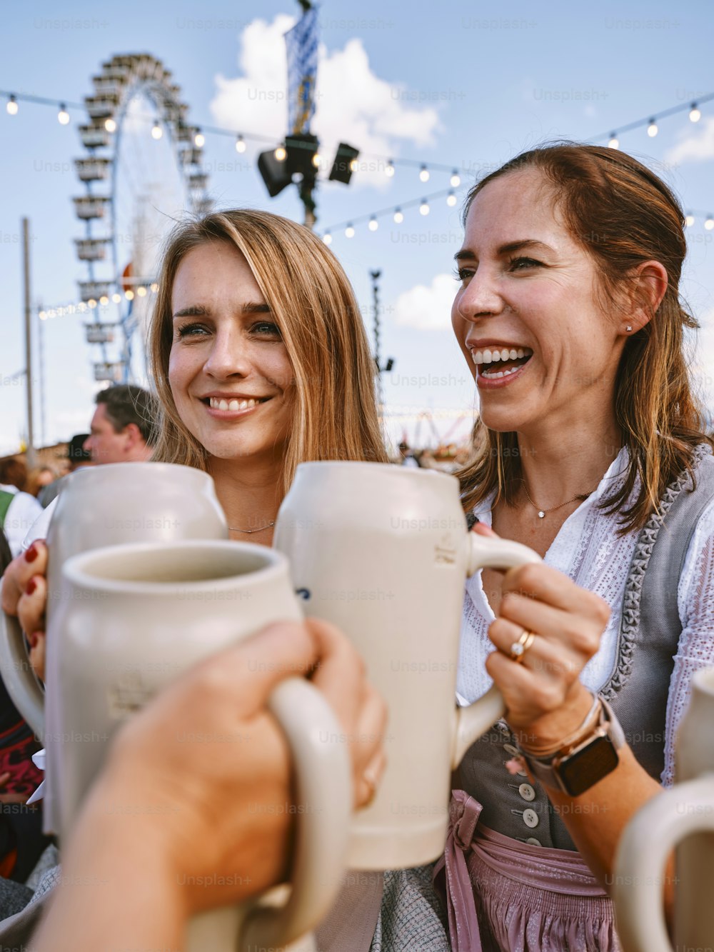 Ein paar Frauen, die nebeneinander stehen und Kaffeetassen halten