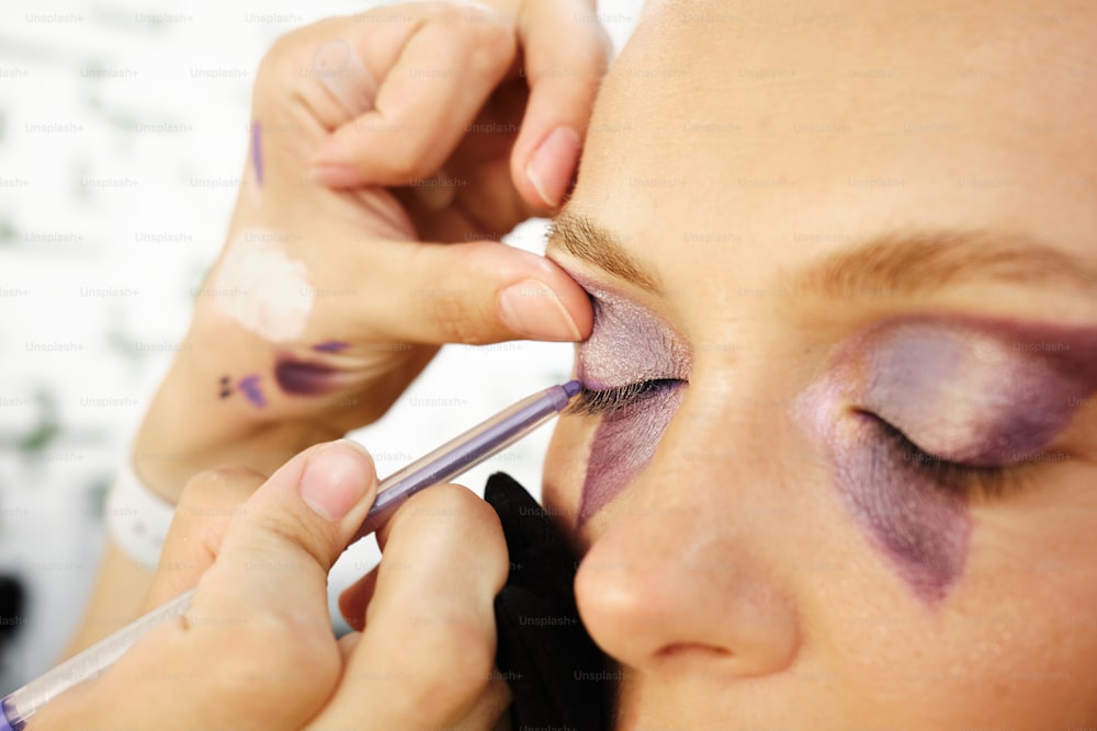 uma mulher fazendo sua maquiagem com um pincel