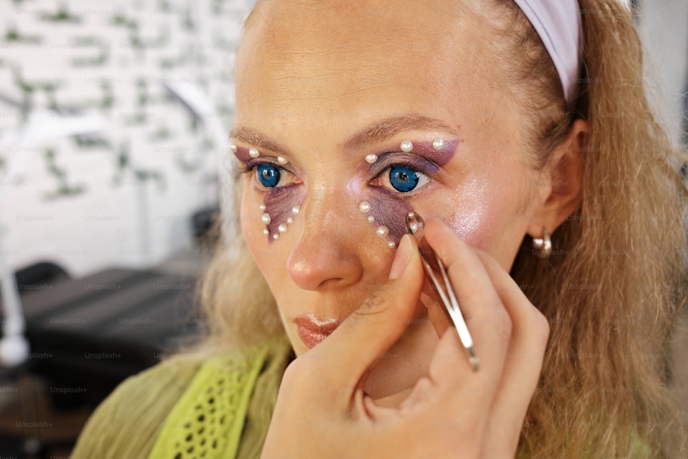 a woman with blue eyes is putting on makeup