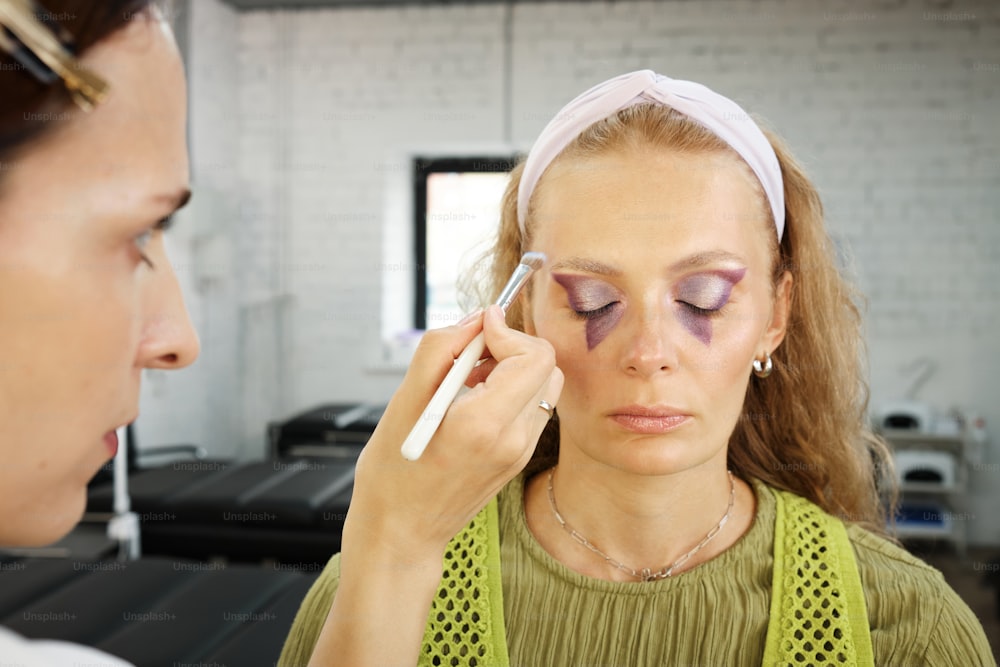 a woman getting her make - up done by another woman