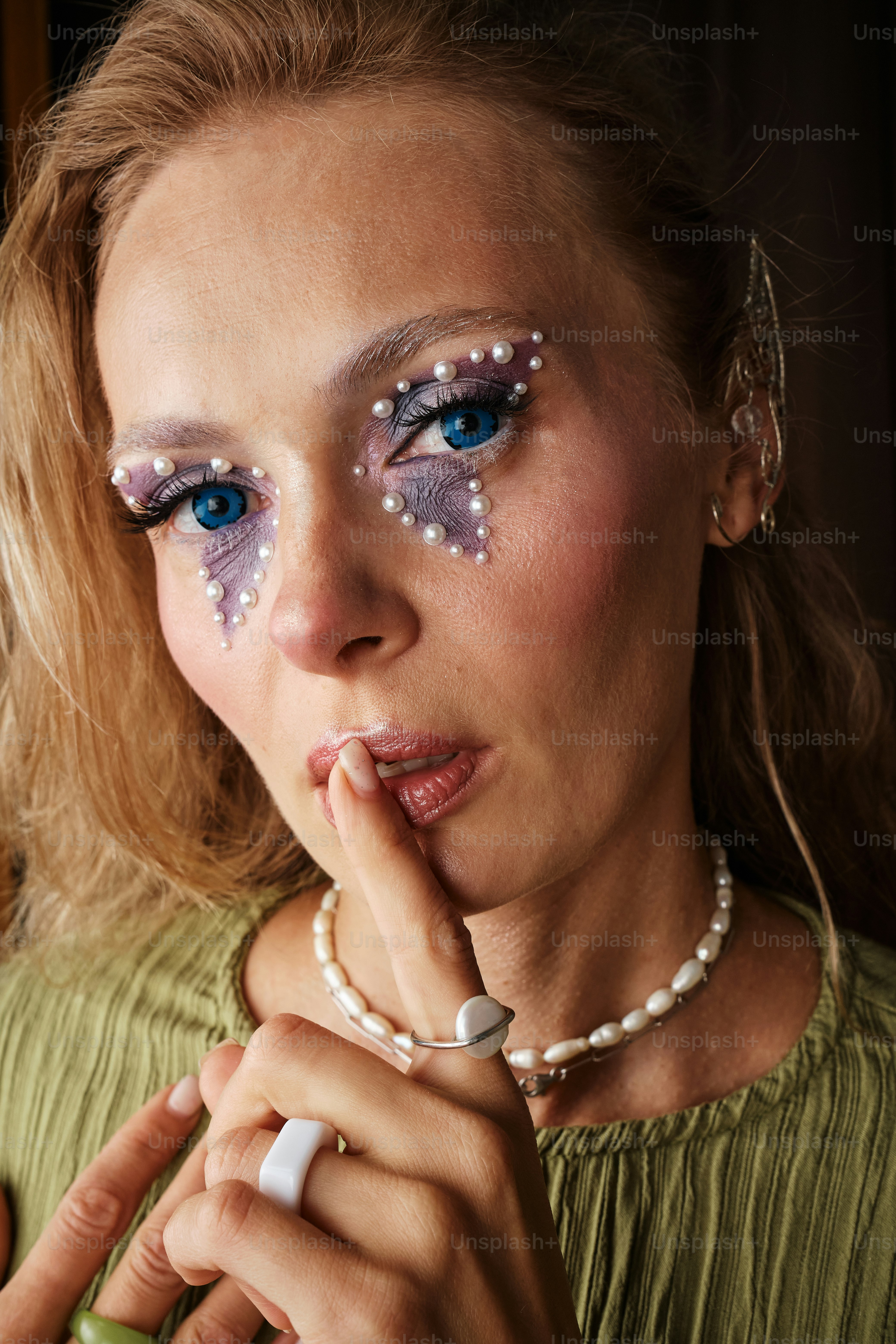 Una donna con il trucco sul viso tiene il dito sulle labbra