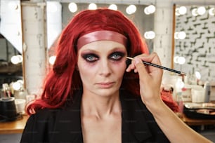 a woman with red hair is doing makeup
