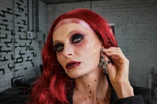 a woman with red hair and makeup is holding a phone to her ear