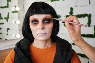 a woman with black hair is doing makeup