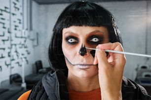 a woman with black makeup is holding a pencil