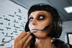 a woman with black hair and makeup is putting makeup on her face