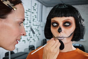 a woman putting makeup on another woman's face