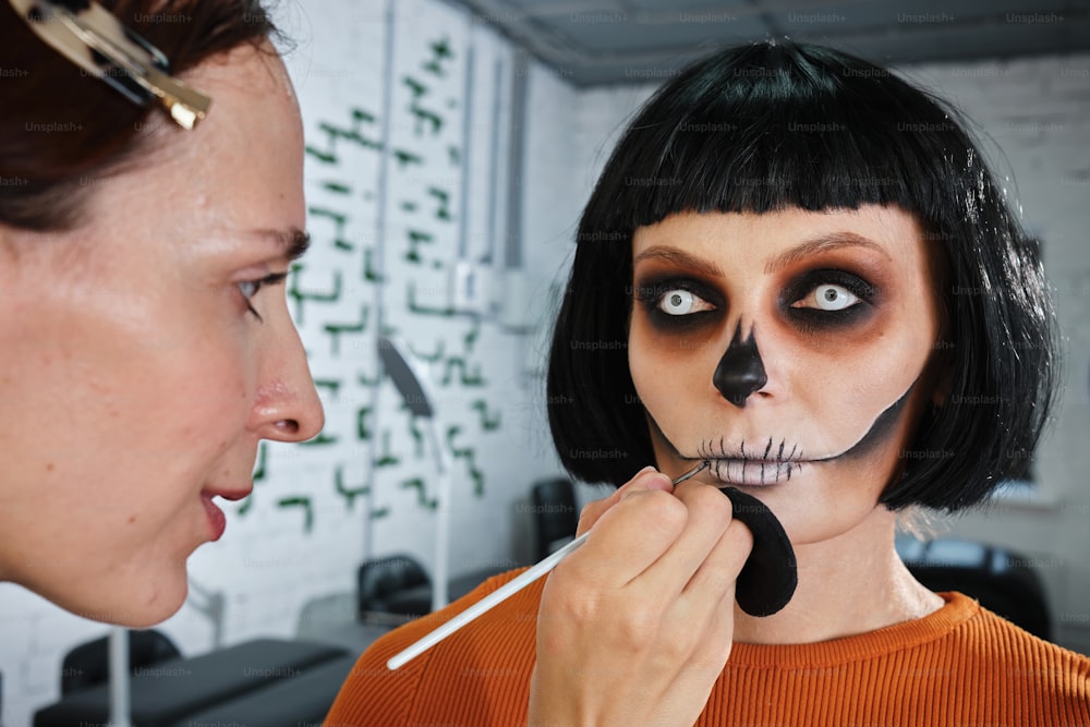 a woman putting makeup on another woman's face