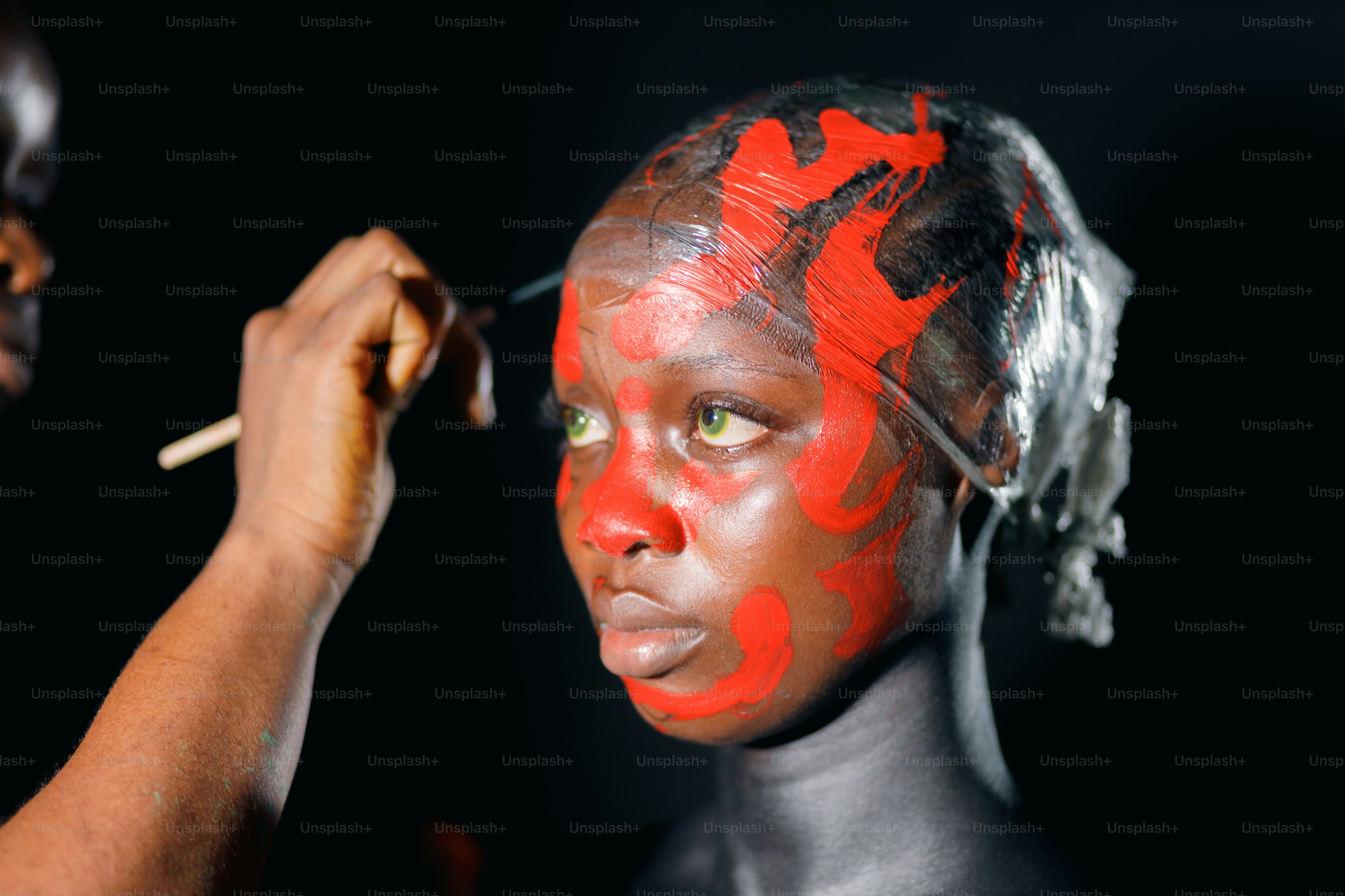 a woman getting her face painted by a man