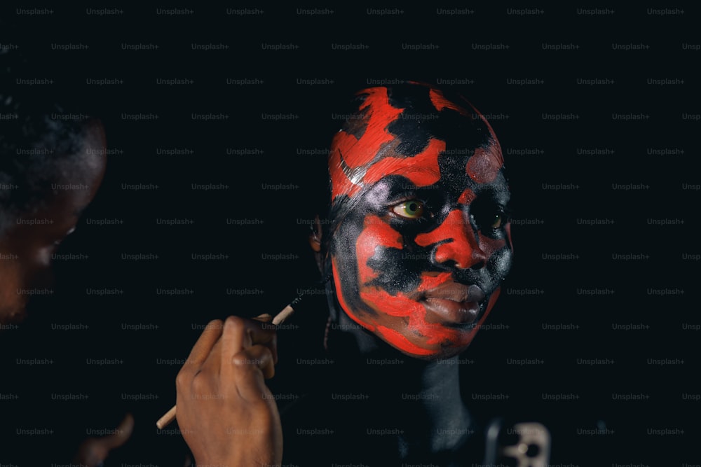 um homem com uma pintura facial vermelha e preta
