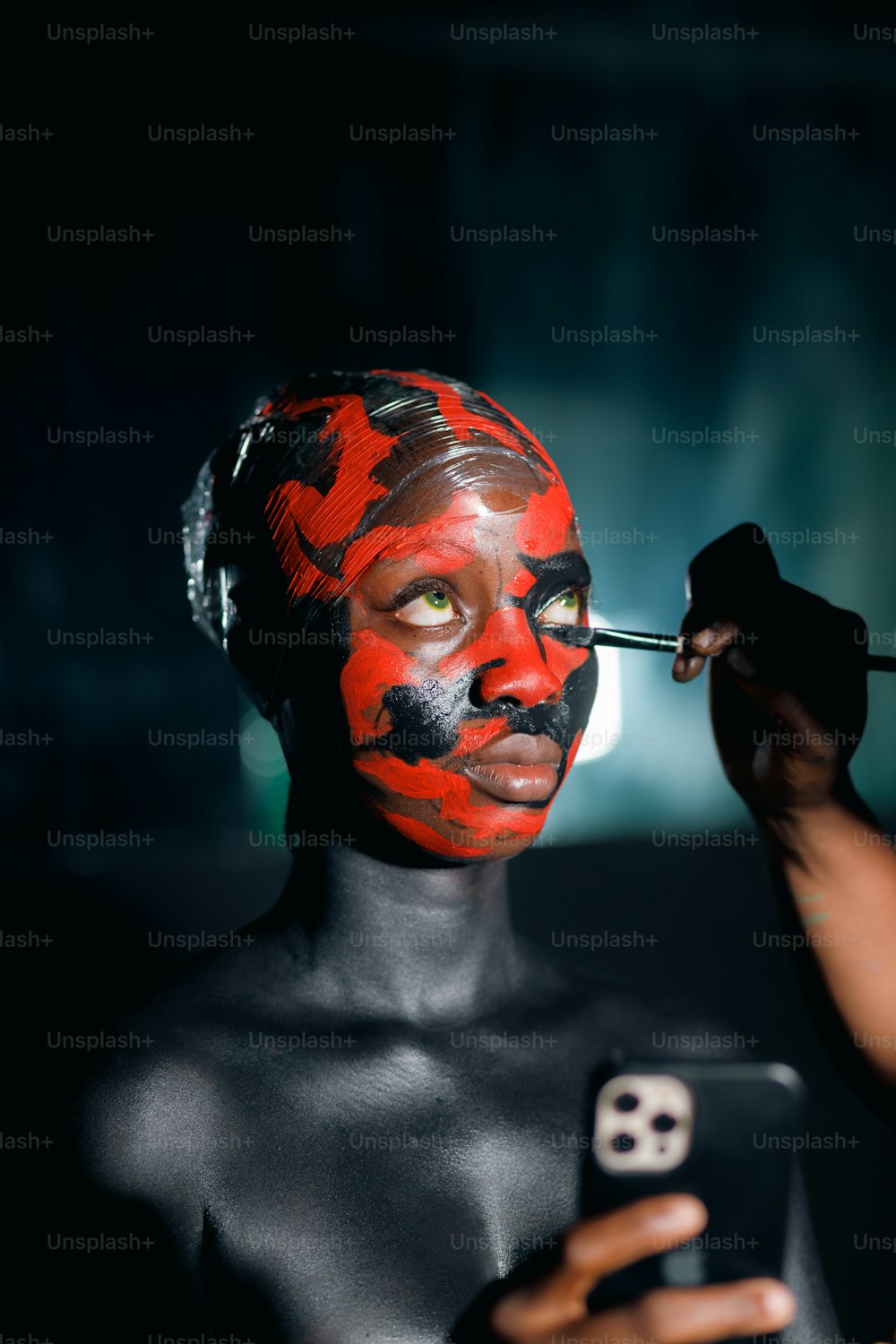 une femme avec de la peinture noire sur le visage utilisant un téléphone portable