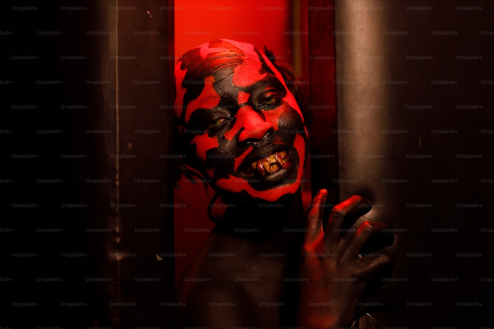 Un uomo con una faccia rossa e nera dipinta