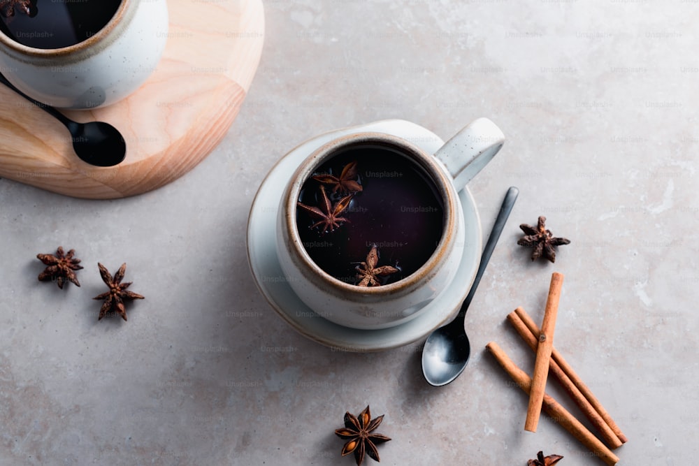 a cup of coffee with cinnamon sticks and star anise on the side