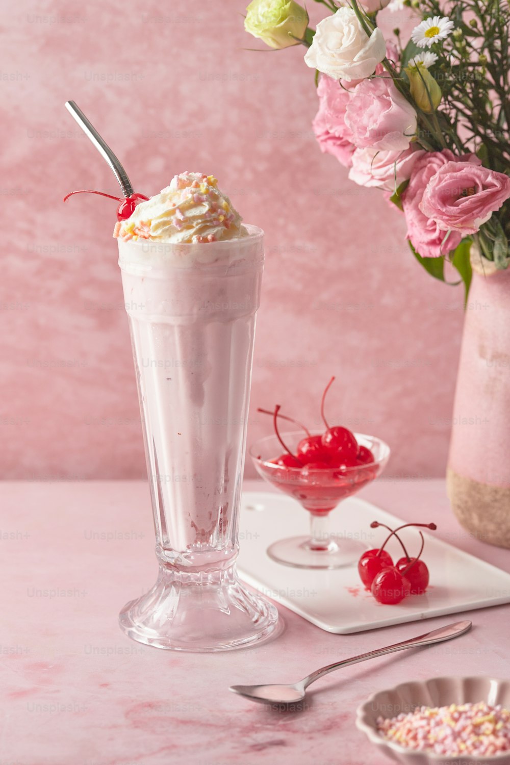 a pink table topped with a tall glass filled with ice cream