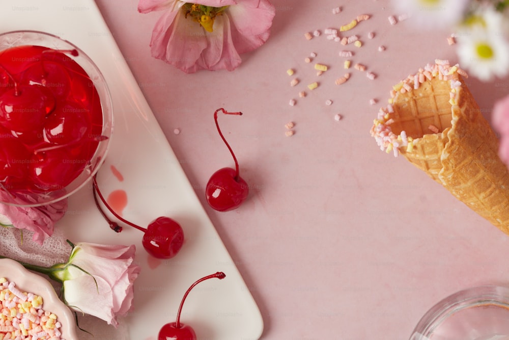 a pink table topped with ice cream and cherries