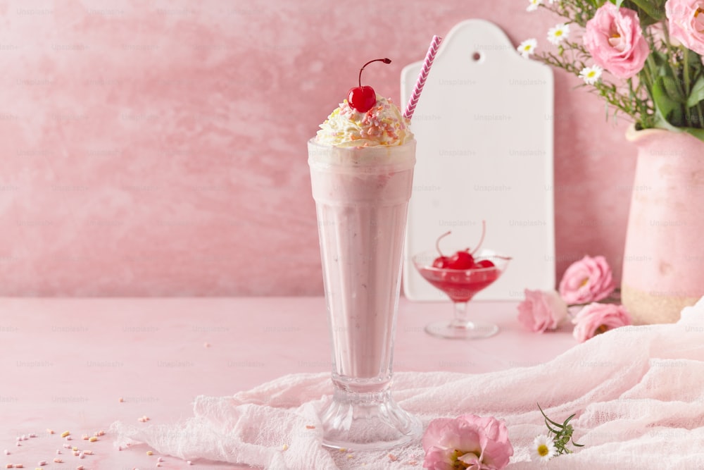 a milkshake with whipped cream and a cherry garnish
