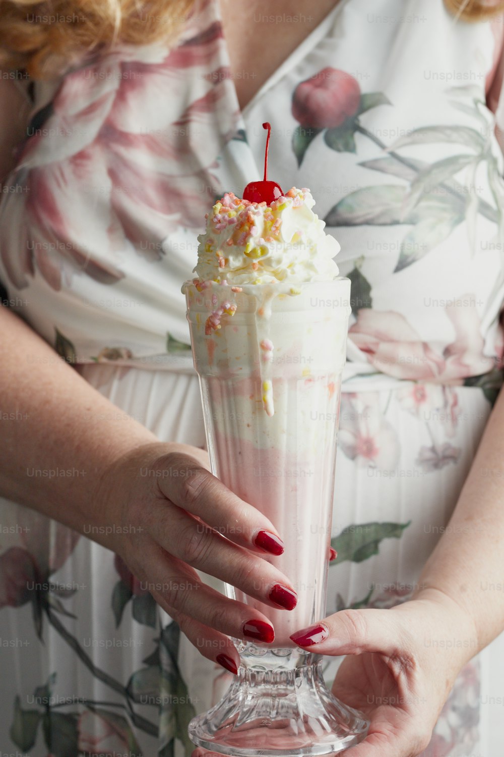 a woman holding a drink with a cherry on top