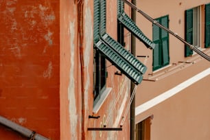 Un edificio con persianas verdes y una pared roja