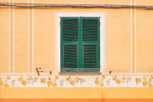 a yellow building with a green window and green shutters