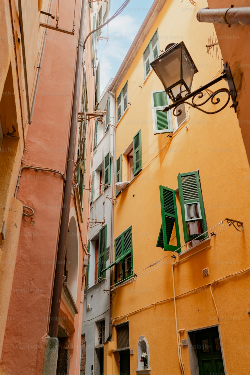 a narrow alleyway with a street light and a yellow building