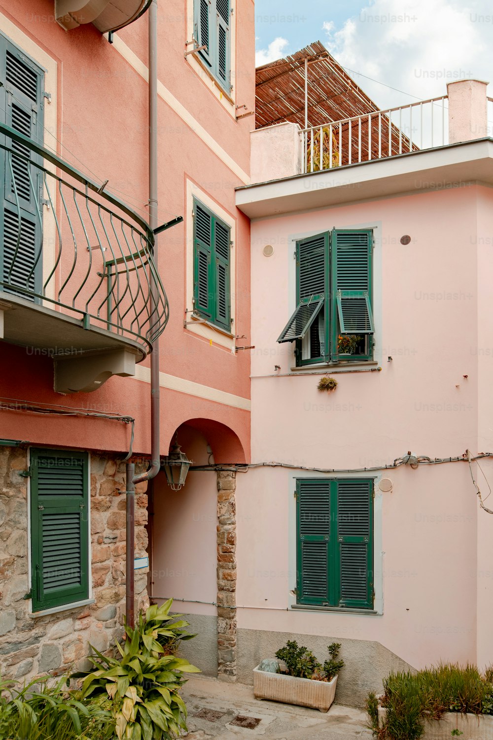 a pink building with green shutters and a balcony