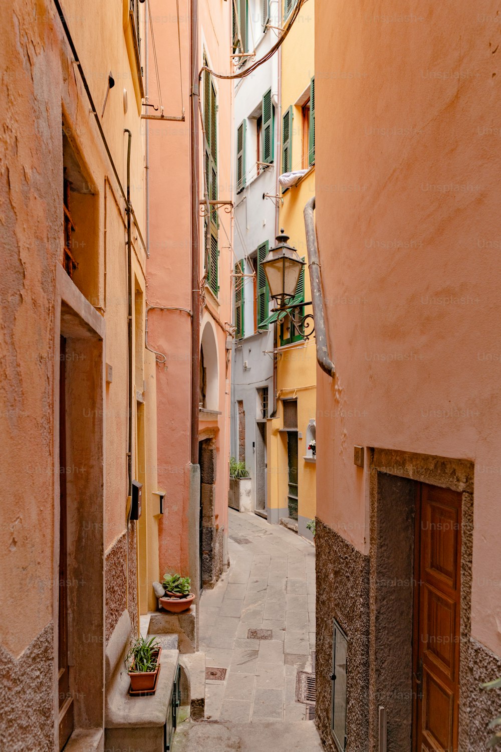 a narrow alley way with buildings and a potted plant
