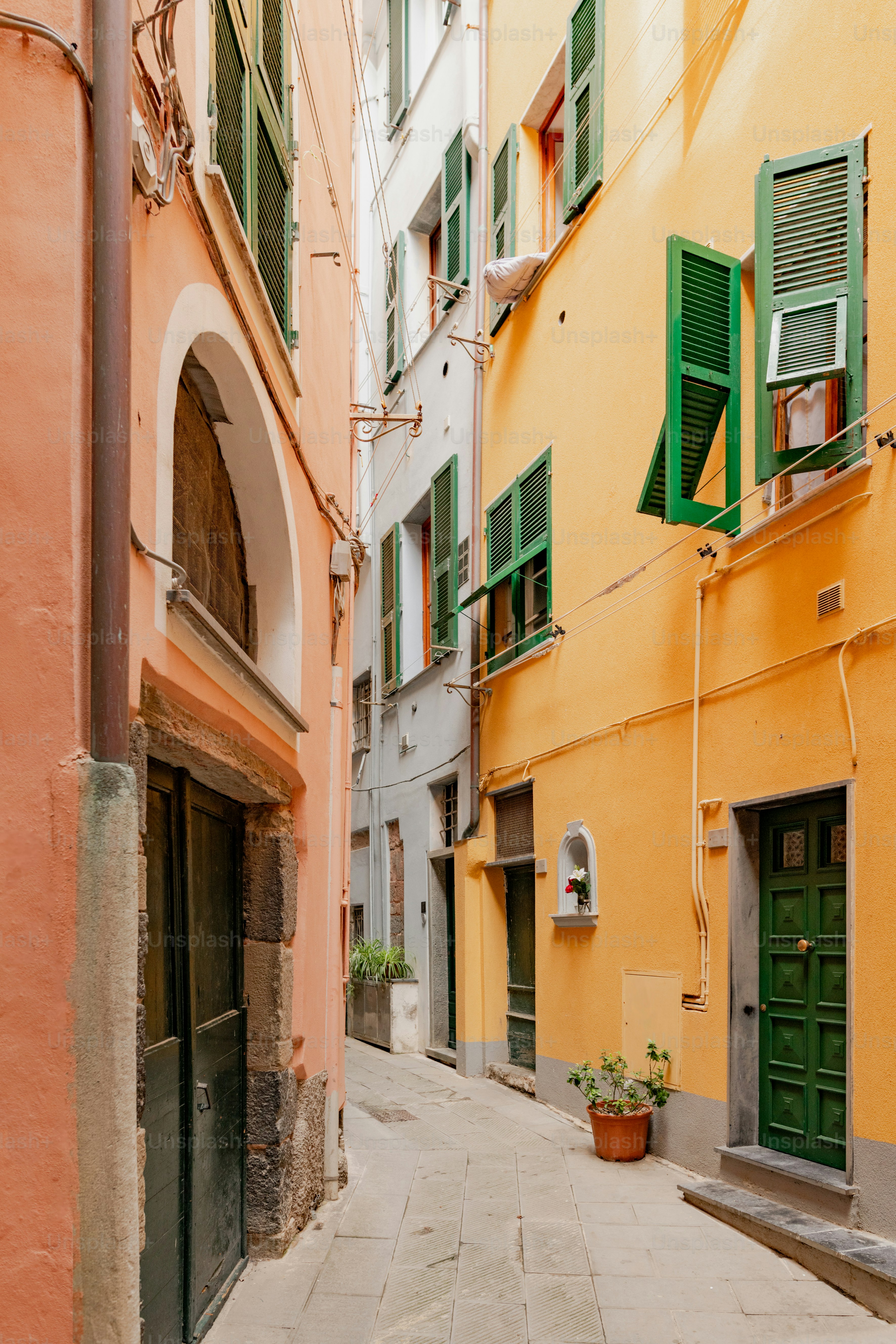 a narrow alleyway with green shuttered windows and green shutters