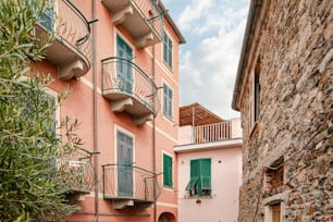 Un callejón estrecho con un edificio rosa y persianas verdes