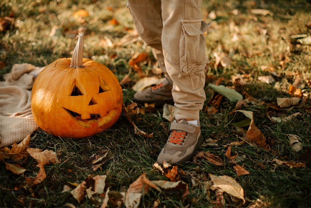a person standing next to a pumpkin on the ground