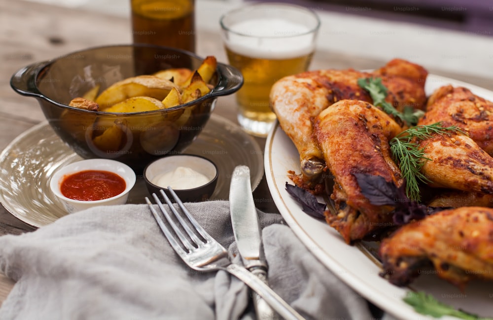 a white plate topped with chicken wings next to a bowl of potatoes