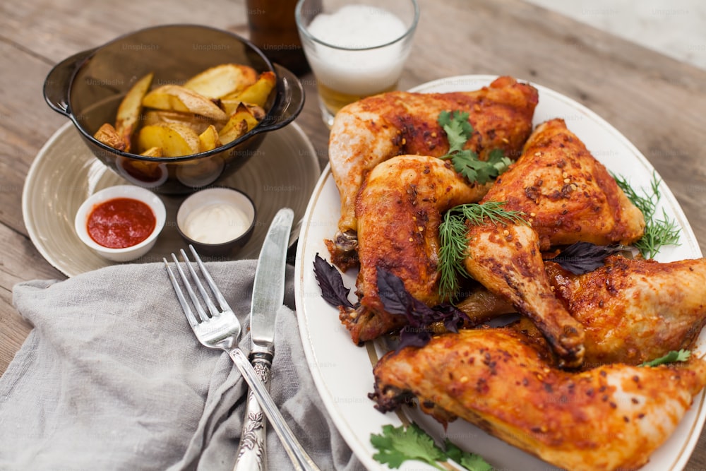 a white plate topped with chicken wings next to a bowl of potatoes