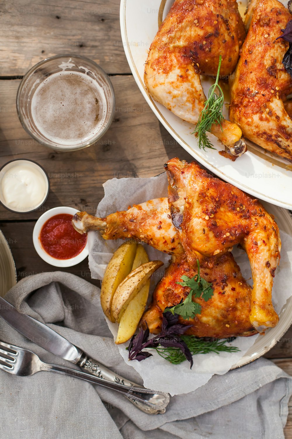 a plate of chicken with a side of potatoes and a glass of beer