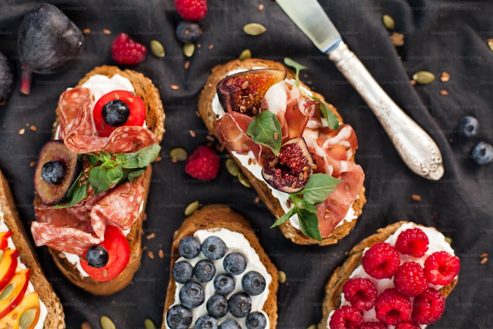 a table topped with breads covered in fruit and veggies