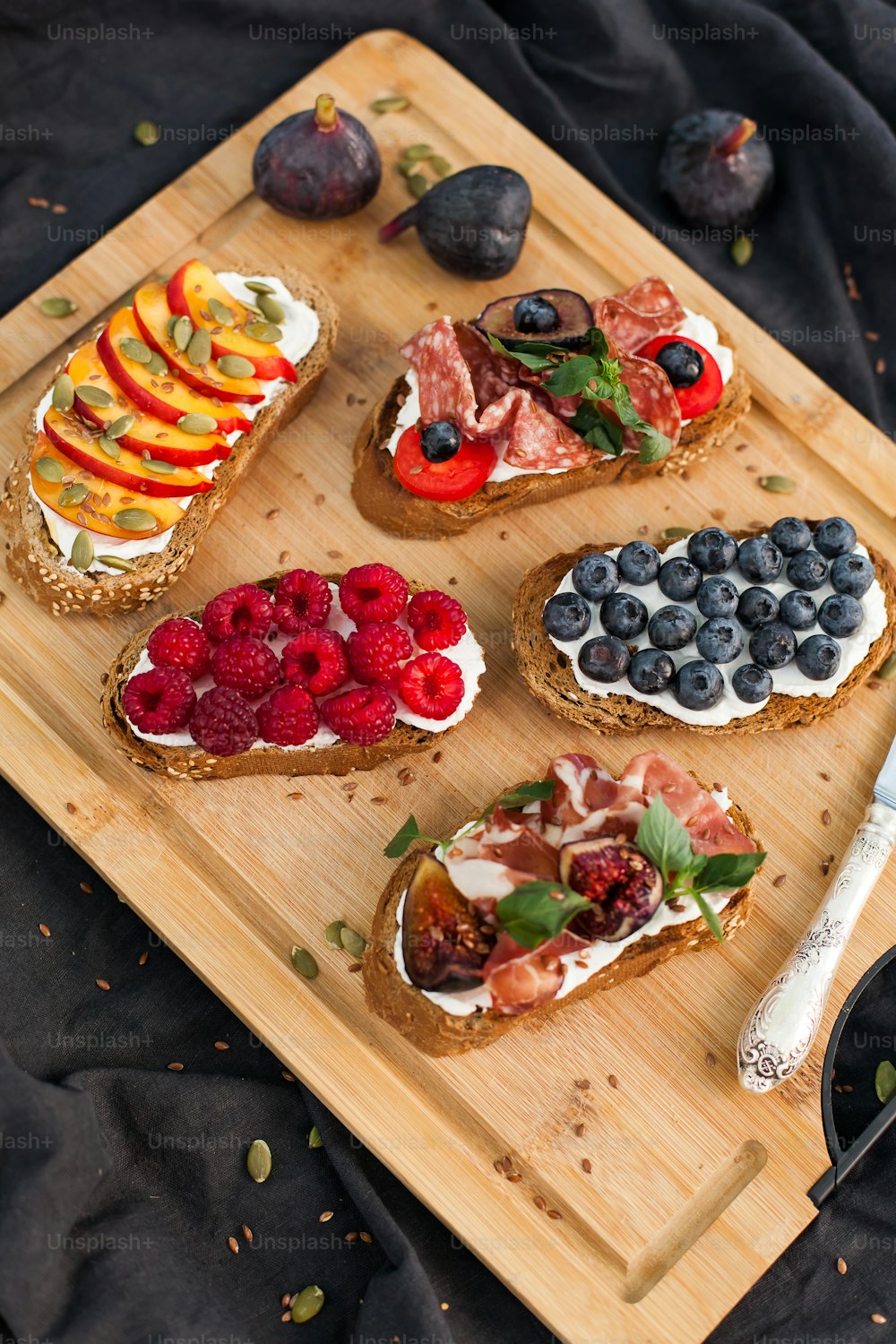 a wooden cutting board topped with slices of bread covered in fruit