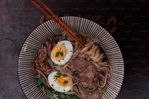 a bowl filled with noodles, meat and eggs