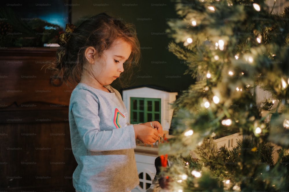 a little girl standing in front of a christmas tree